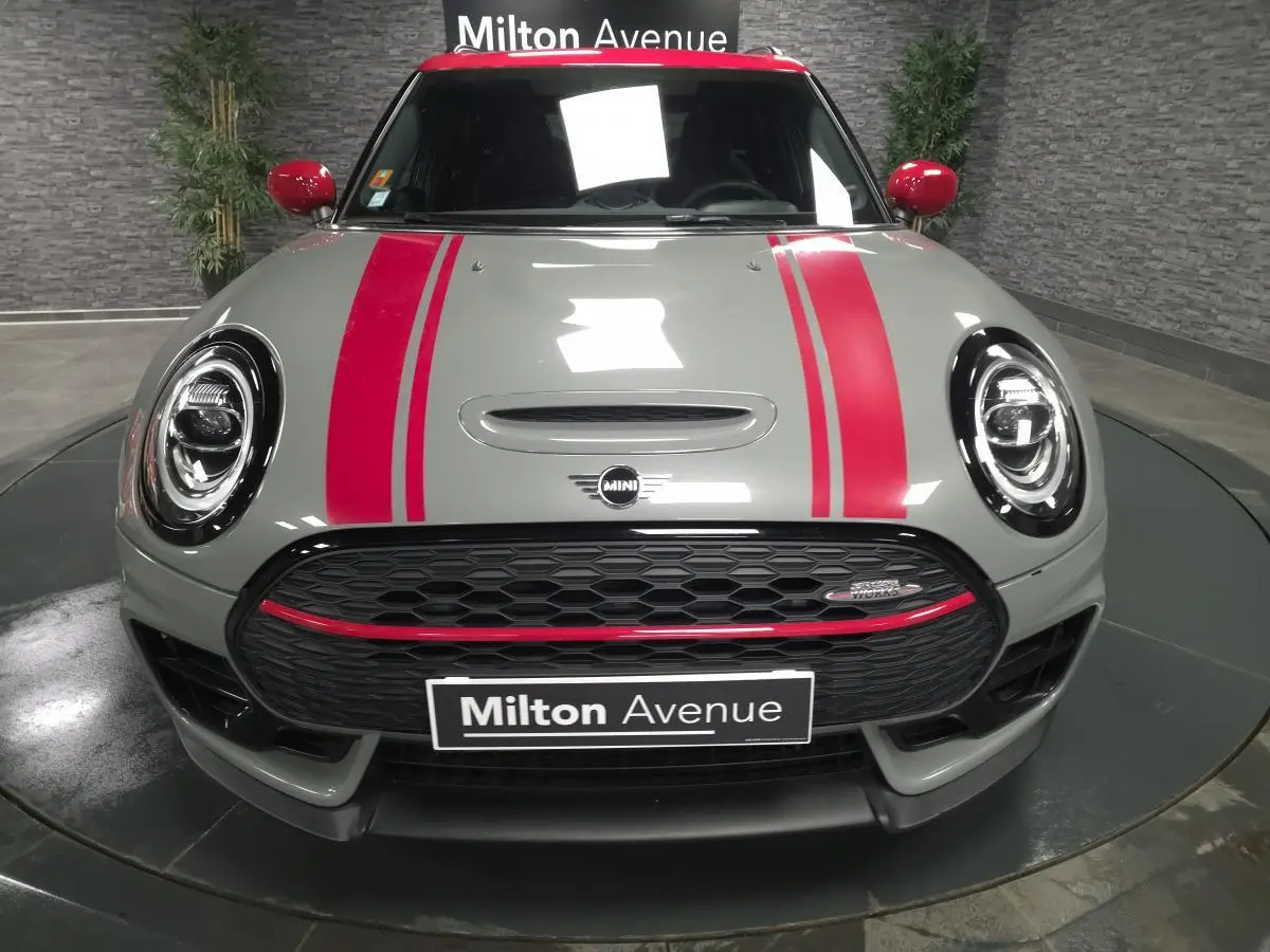Vue frontale d'une MINI Clubman gris Moonwalk avec bandes rouges sport et calandre noire John Cooper Works.