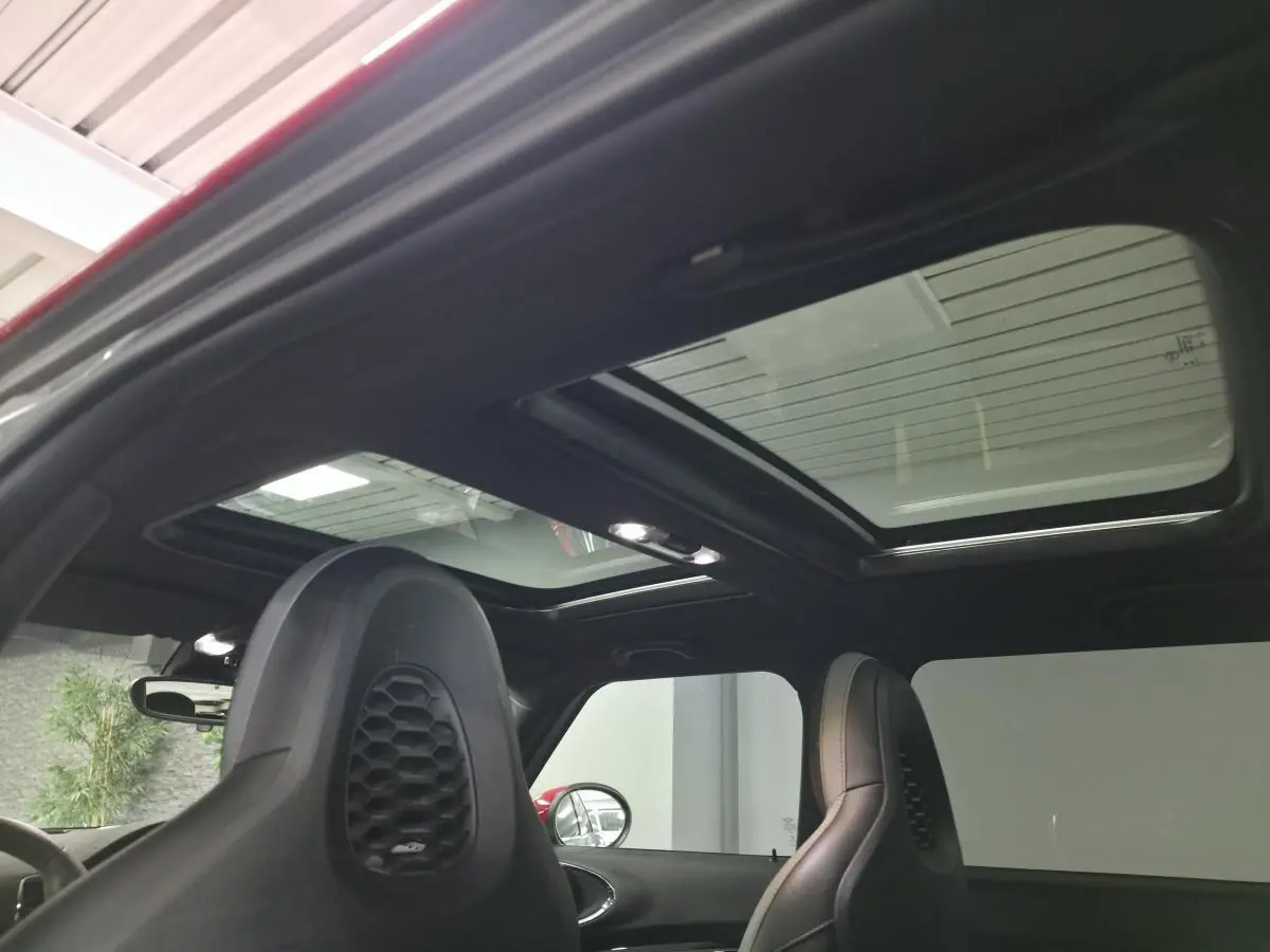 Vue intérieure du toit ouvrant panoramique et des sièges avant en cuir noir du MINI Clubman John Cooper Works gris.
