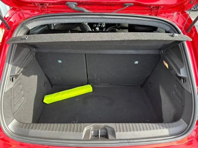 Coffre ouvert vu de dessus d'une Renault Clio Rouge Flamme 2025, avec un objet jaune fluorescent à l'intérieur.