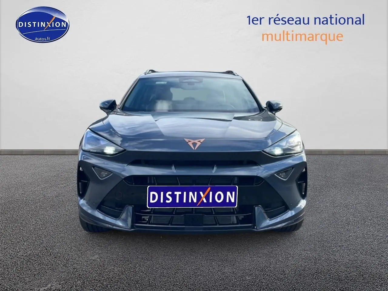 Vue frontale d'une CUPRA Formentor gris magnétique 2026 avec feux LED allumés et logo cuivre distinctif.