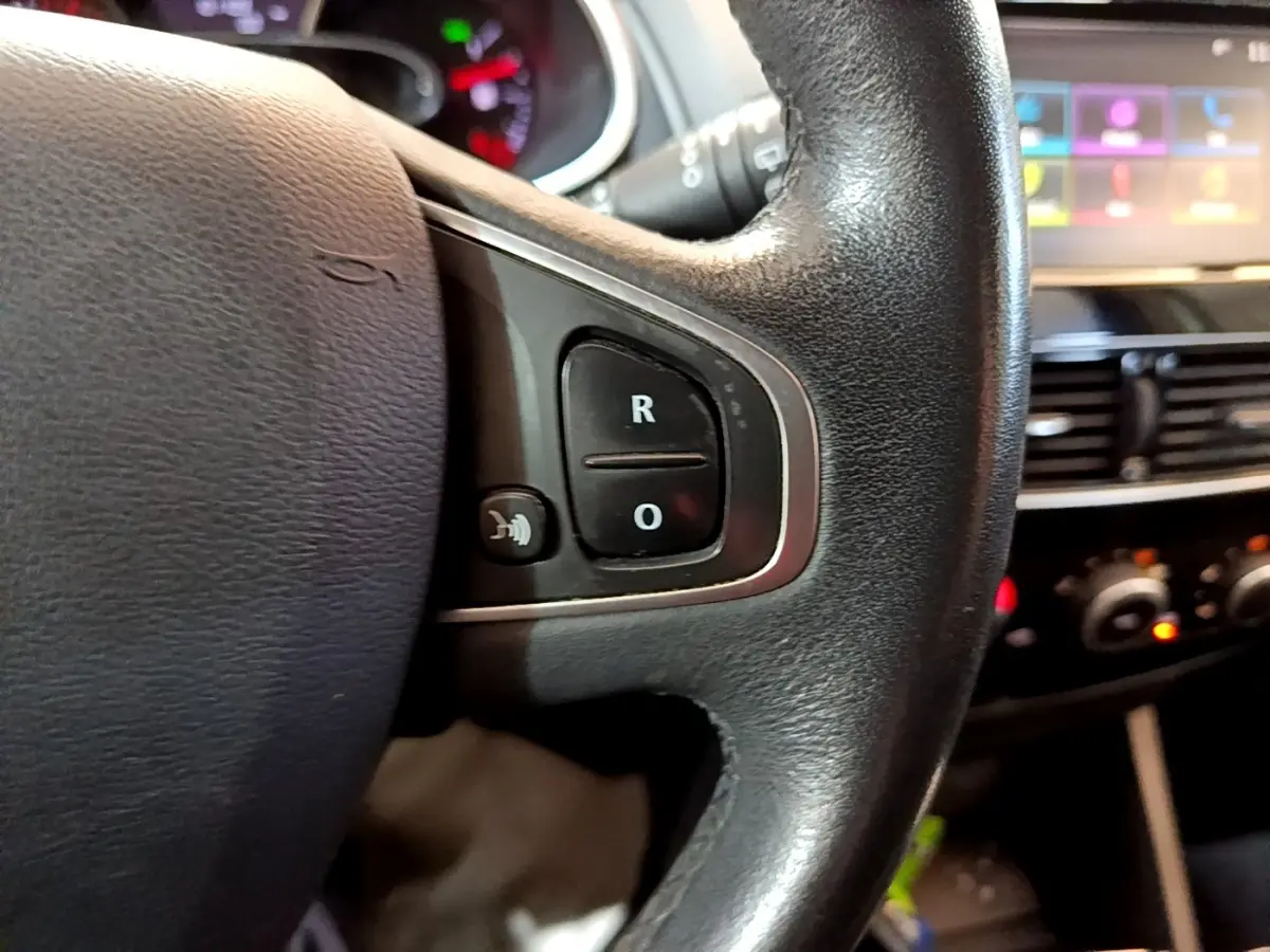 Gros plan sur le volant cuir noir de la Renault Clio Zen Energy dCi 75, avec commandes multifonctions visibles.