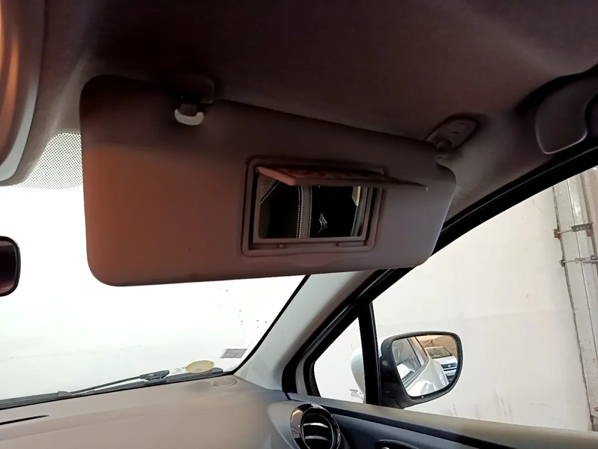 Détail intérieur montrant le pare-soleil côté conducteur avec miroir et rétroviseur extérieur d’une Renault Clio blanche.