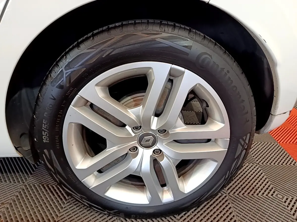 Gros plan sur la roue avant droite d'une Renault Clio blanche, jante alliage à cinq branches doubles.