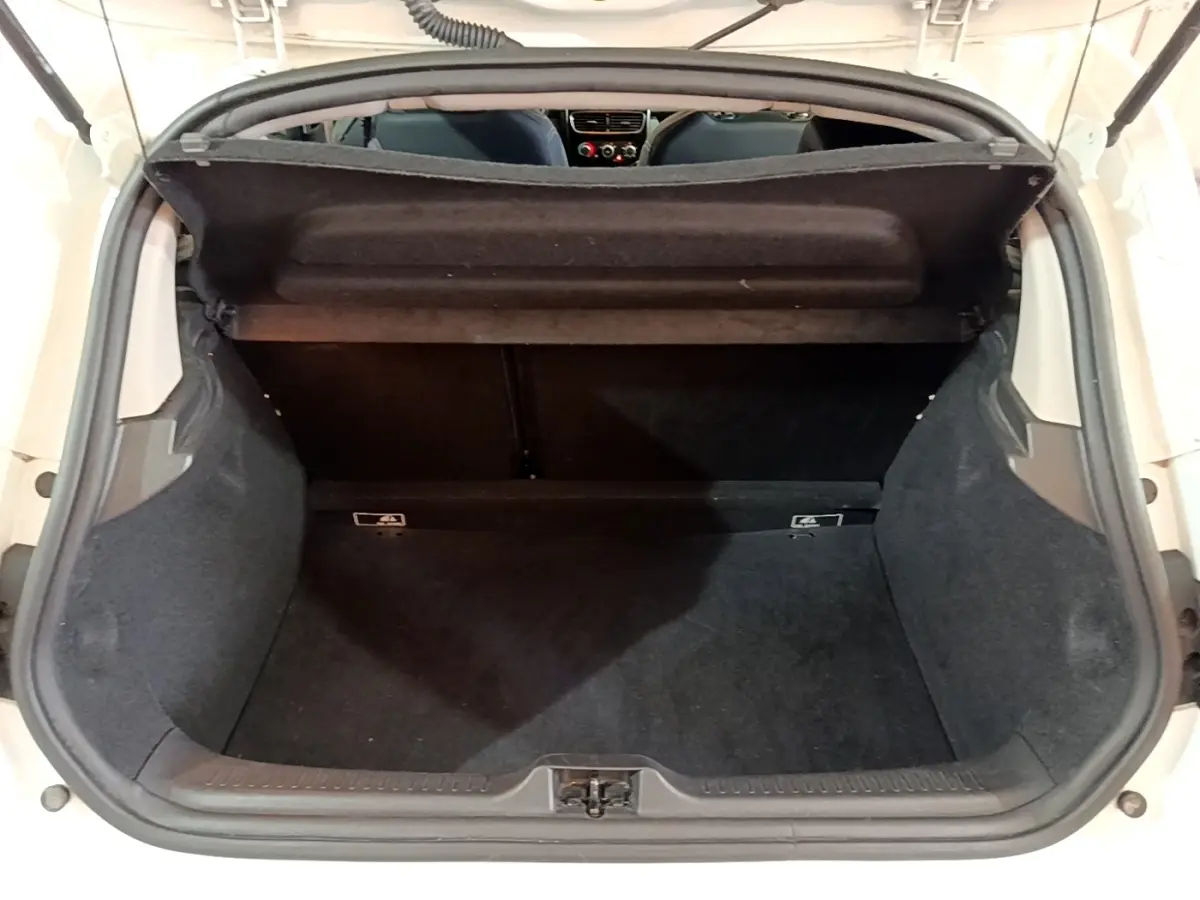 Vue arrière du coffre ouvert d'une Renault Clio blanche, montrant l'espace de chargement et la banquette arrière.