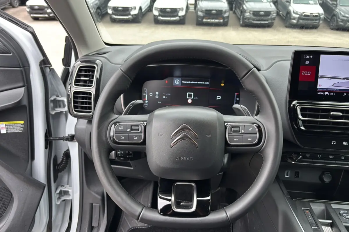 Vue intérieure centrée sur le volant cuir multifonctions du Citroën C5 Aircross blanc, avec tableau de bord digital et écran tactile.