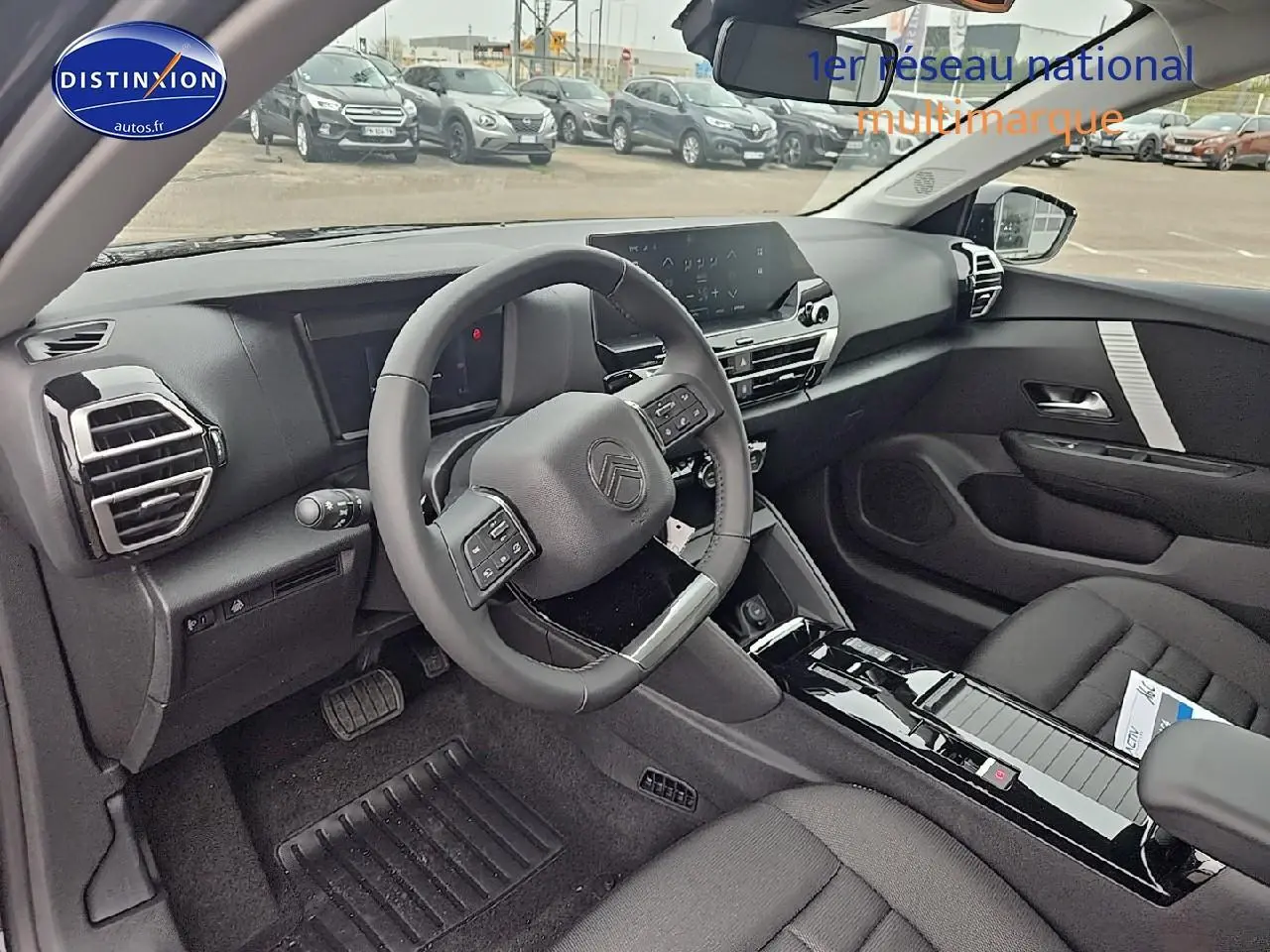 Intérieur avant droit de la Citroën C4 1.2 hybride 136 plus avec tableau de bord noir et volant cuir.