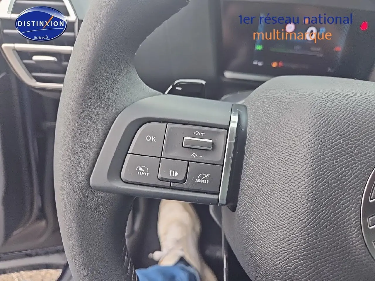 Gros plan sur les commandes au volant gauche d'une Citroën C4 1.2 hybride 136 plus, intérieur noir.