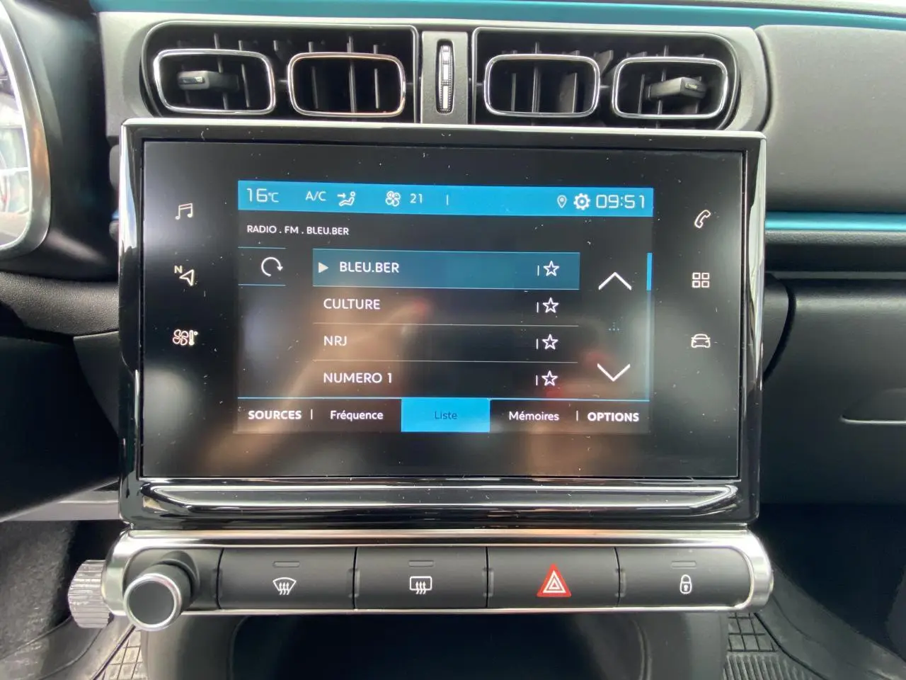 Écran tactile central de la Citroën C3 2021 noir, affichant la liste des stations radio avec commandes climatisation en dessous.