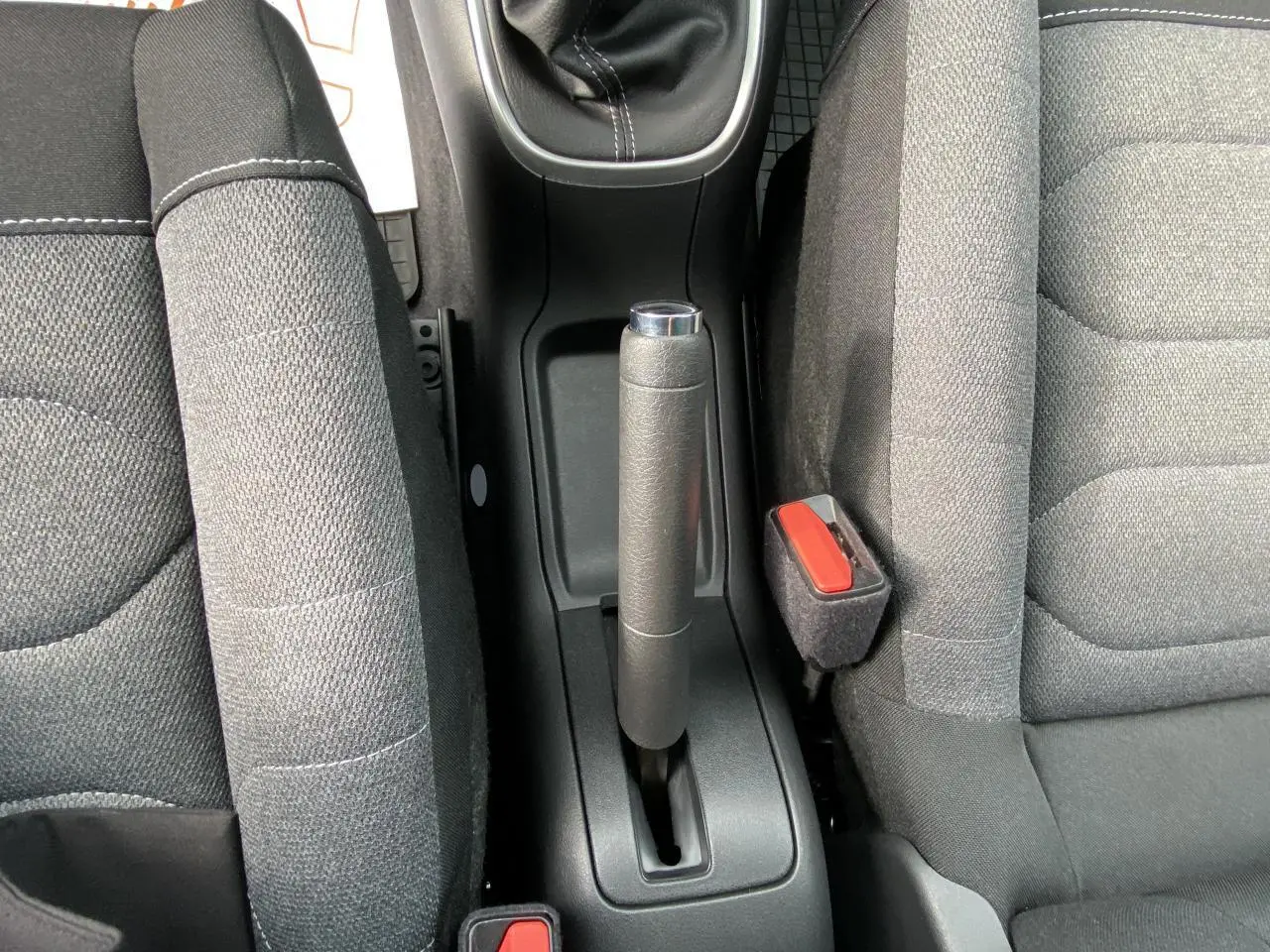 Vue rapprochée du frein à main manuel entre les sièges avant gris foncé d'une Citroën C3 1.2 PureTech essence.