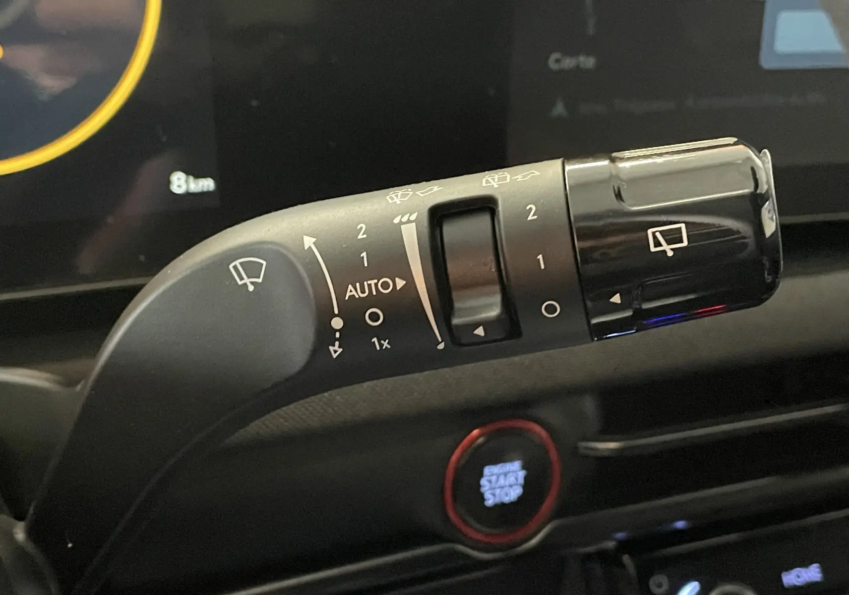 Gros plan sur la commande d’essuie-glace du Hyundai Tucson gris Ecotronic 2025, avec bouton start/stop en arrière-plan.