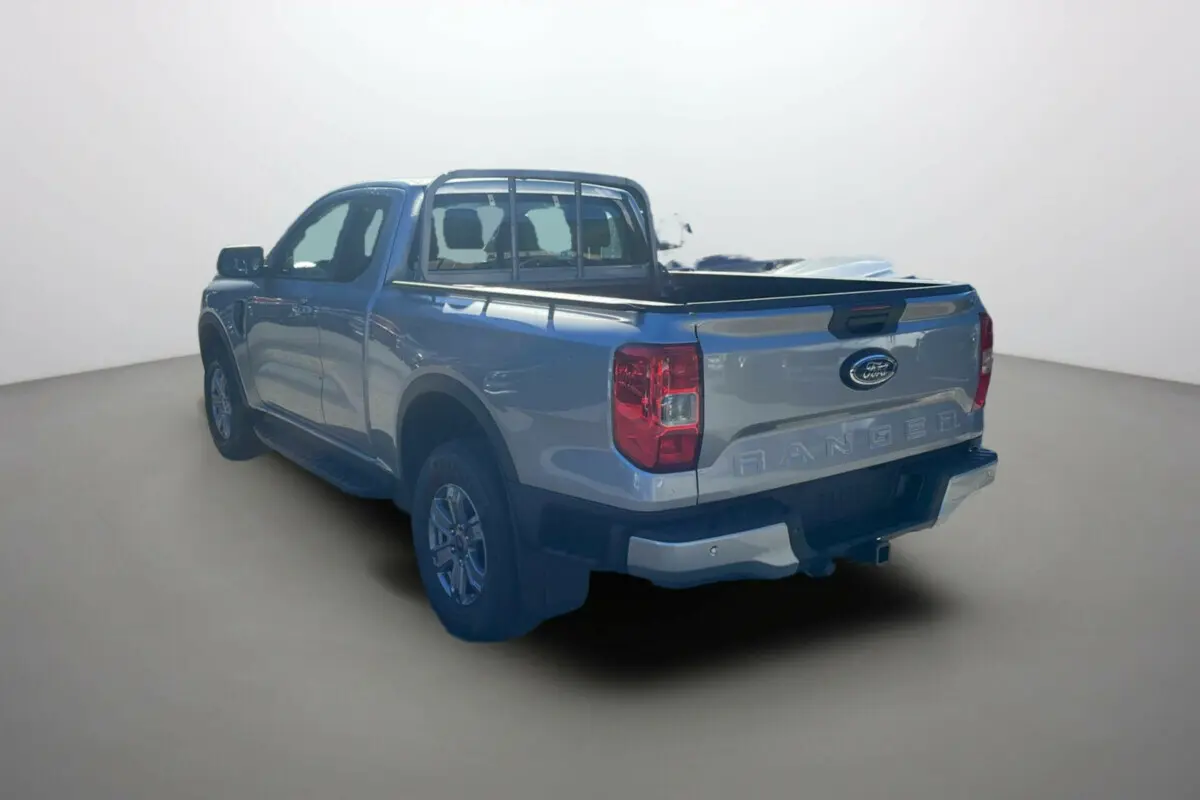 Ford Ranger gris iconic en 3/4 arrière droit, avec benne ouverte et marchepieds latéraux visibles.