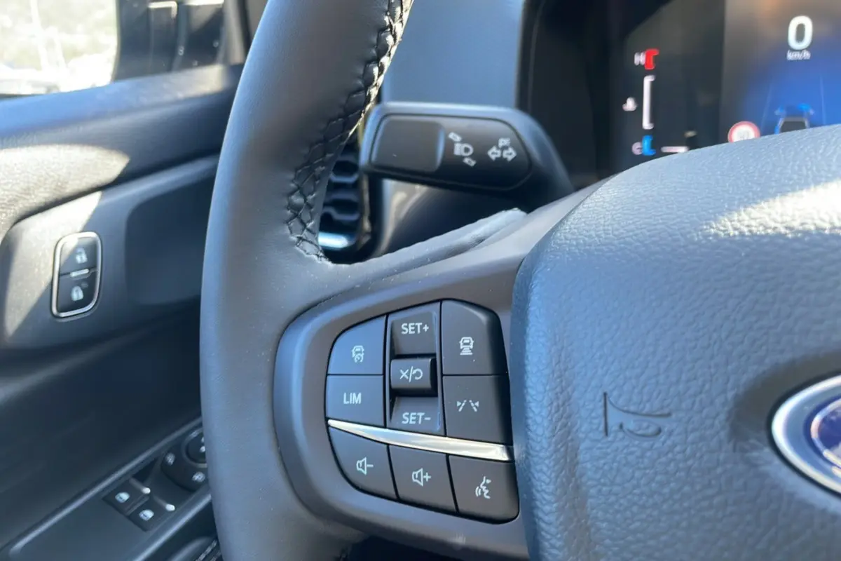 Gros plan sur le volant cuir multifonctions du Ford Ranger 2025, avec commandes intégrées et tableau de bord partiel visible.