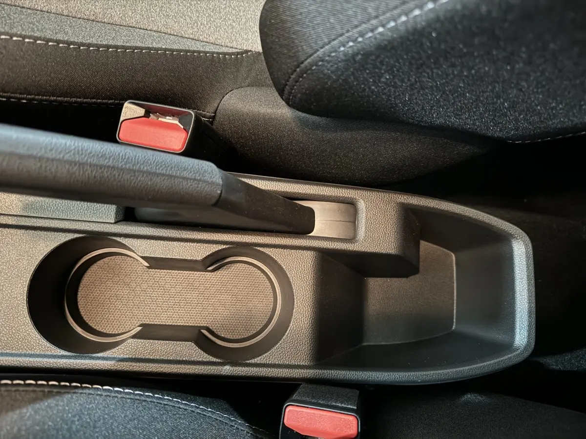 Vue plongeante sur la console centrale noire de la Renault Clio gris clair, avec frein à main et porte-gobelets visibles.