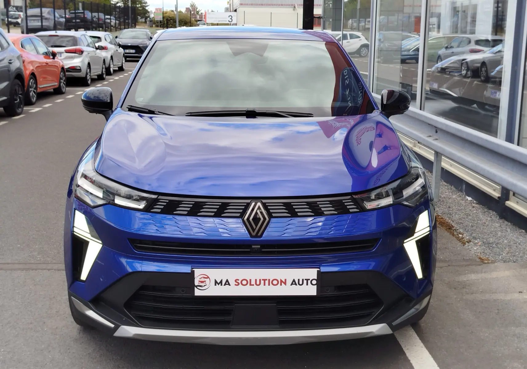 Vue frontale d'une Renault Symbioz bleu iron metal avec feux LED allumés et calandre noire brillante.