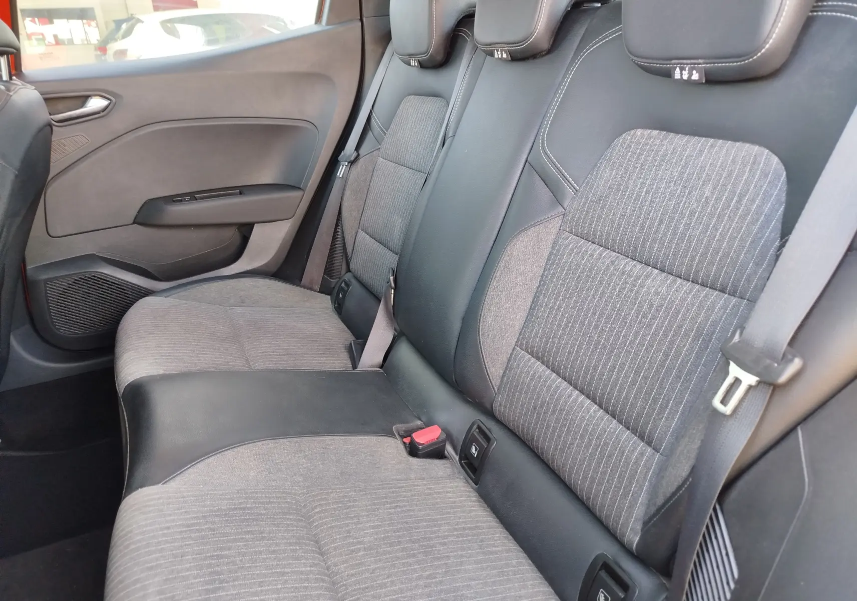 Vue intérieure côté droit des sièges arrière gris et noir de la Renault Clio 1.6 E-Tech hybride 2022, avec ceintures et appuie-têtes.