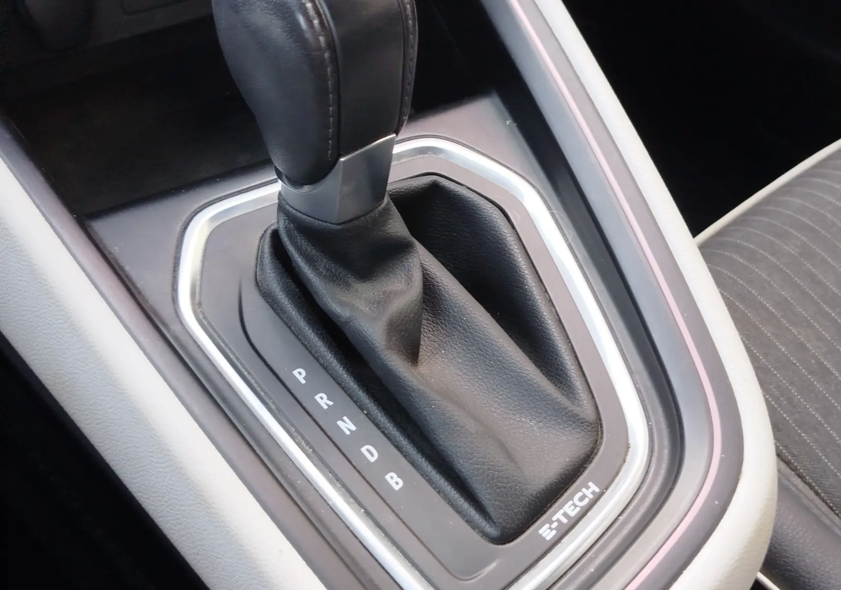 Gros plan sur le levier de vitesses automatique noir avec surpiqûres, entouré d’un cadre argenté marqué E-TECH dans une Renault Clio.