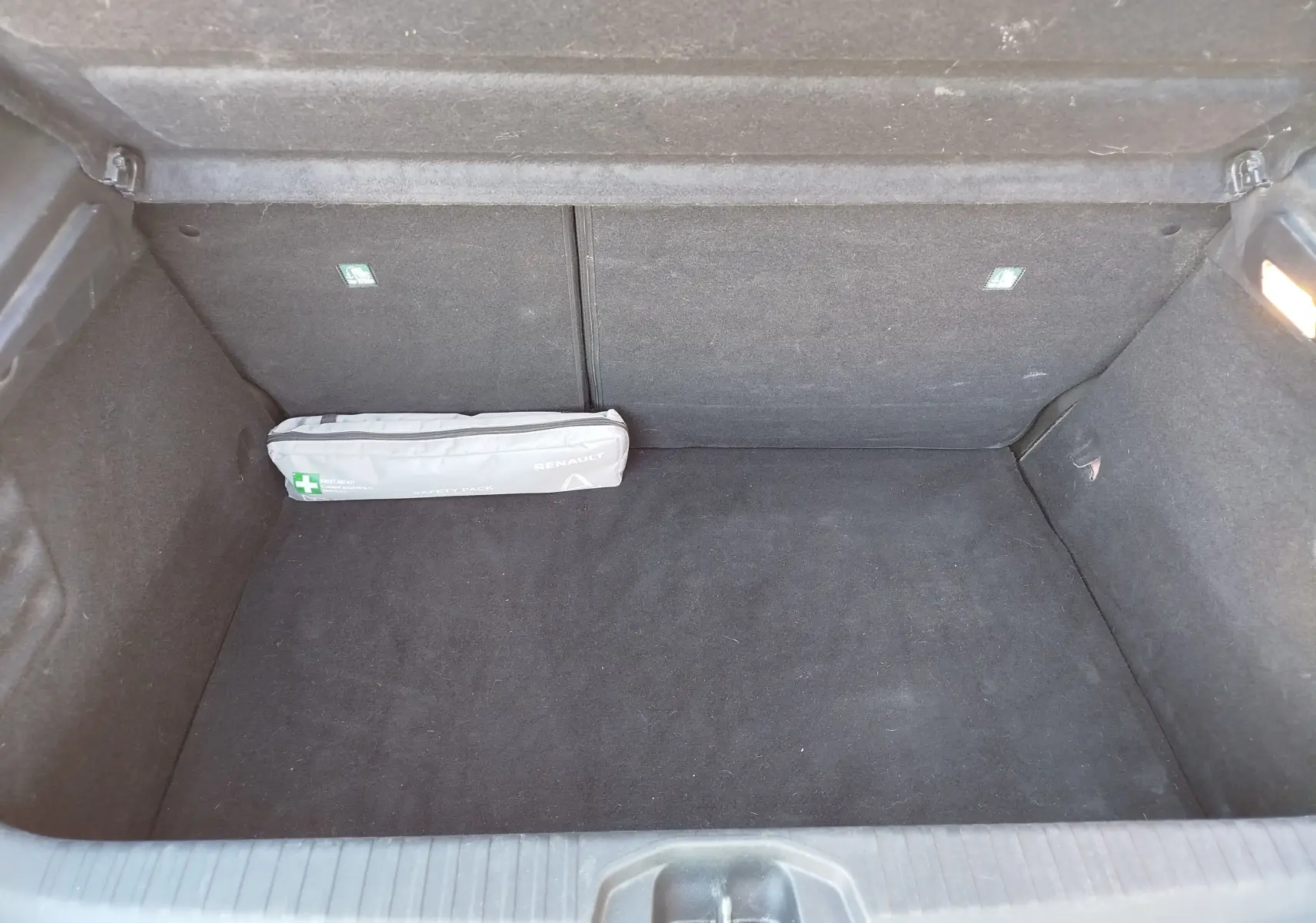 Coffre ouvert d'une Renault Clio 1.6 E-Tech hybride 2022, vue intérieure montrant un kit de sécurité gris.