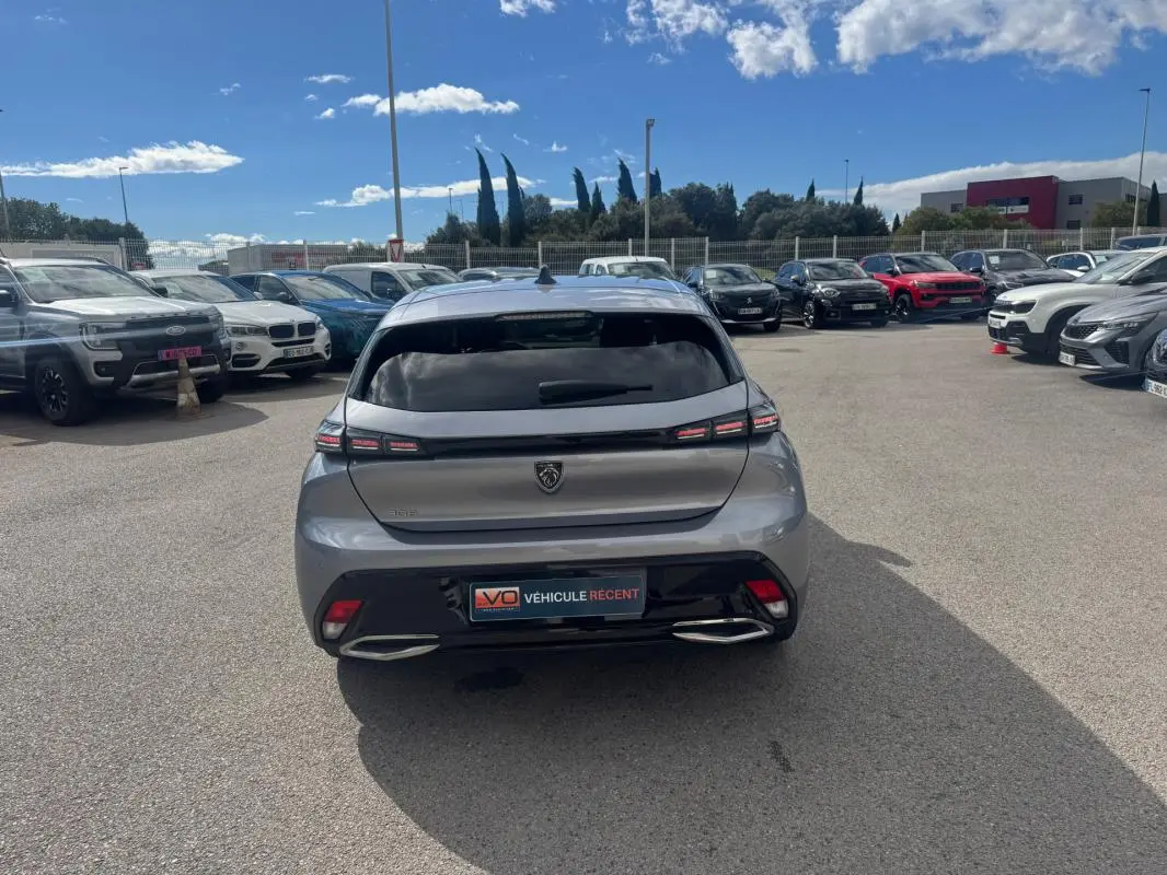 Vue arrière d'une Peugeot 308 Hybrid 145 gris métallisé, avec feux LED distinctifs et double sortie d'échappement intégrée.