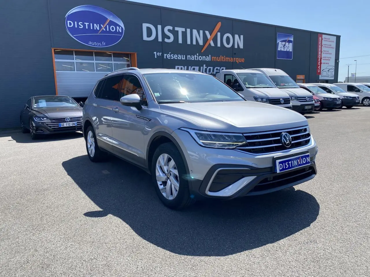 Volkswagen Tiguan Allspace gris argent pyrite métallisé en 3/4 avant droit sur parking extérieur devant concession