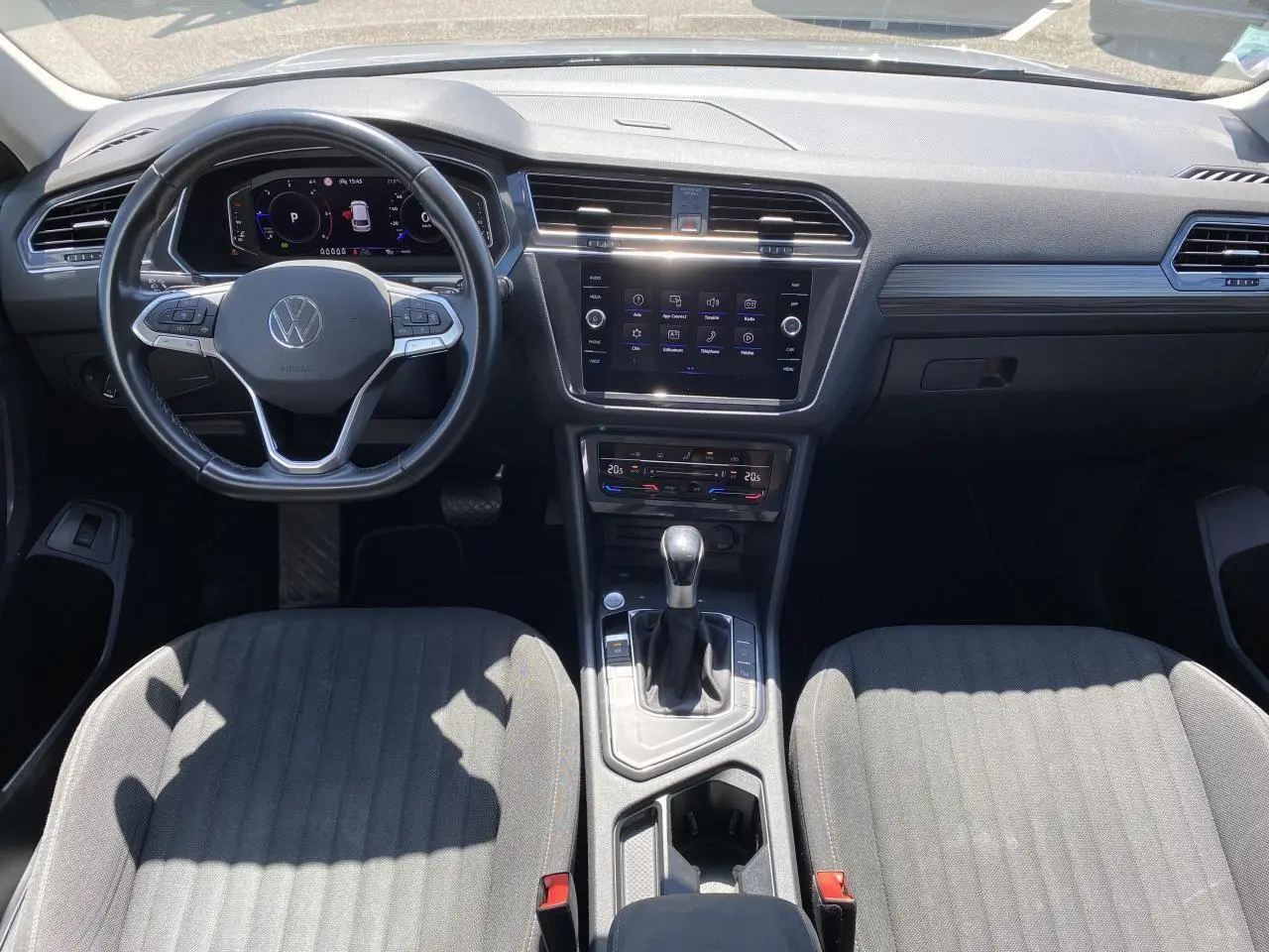 Vue intérieure avant du Volkswagen Tiguan Allspace 2022, tableau de bord moderne avec écran tactile et sellerie tissu gris.