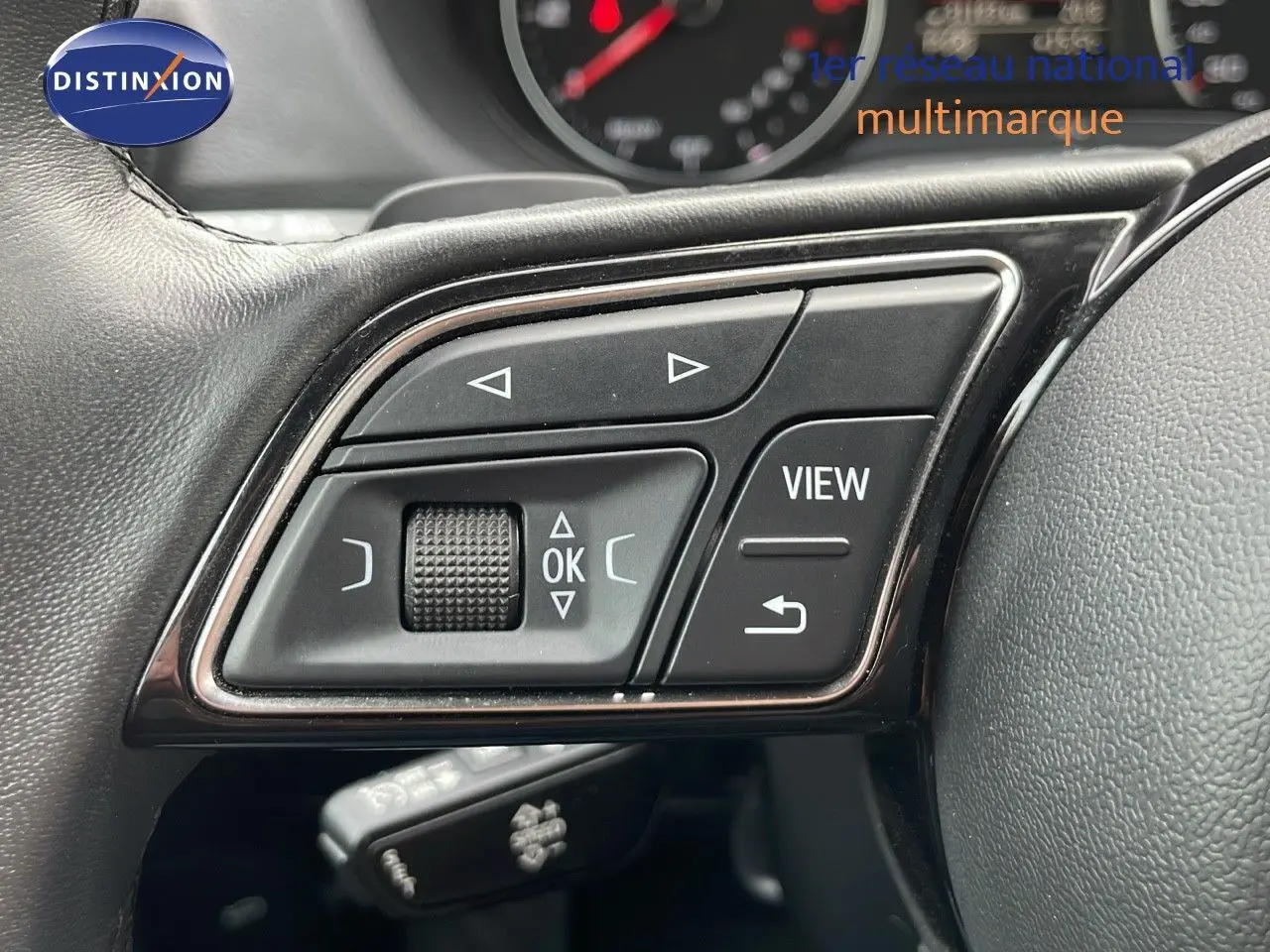 Gros plan sur les commandes au volant noir d'un Audi Q2 35 TFSI S-Line 2023, avec boutons multifonctions visibles.