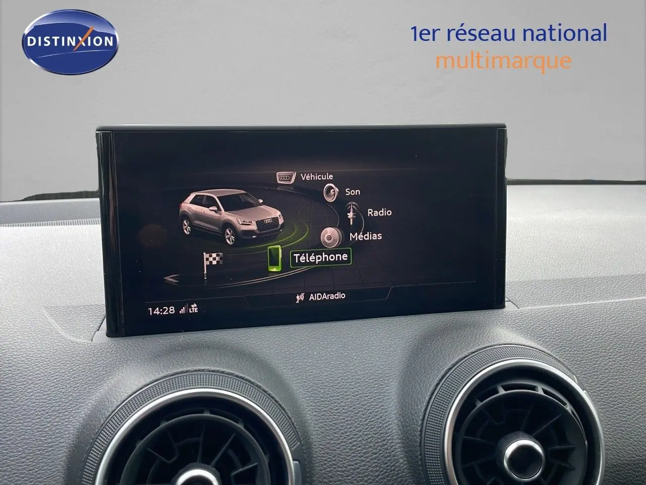 Écran central affichant le menu multimédia avec une image du SUV Audi Q2 noir mito metal en vue latérale intérieure.