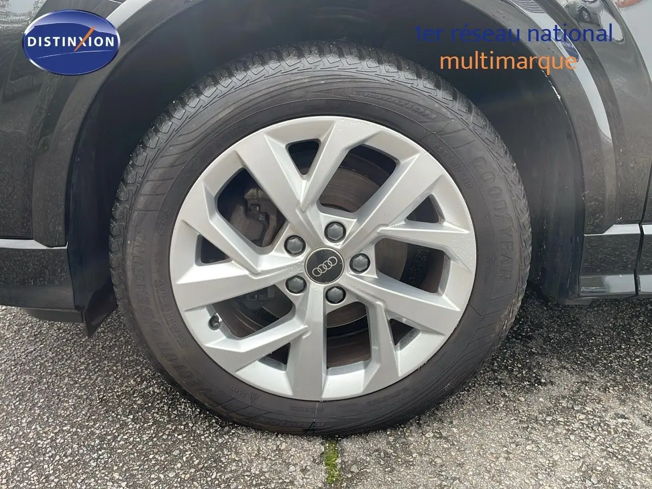 Gros plan sur la roue avant gauche avec jante argentée d'un Audi Q2 noir Mito Metal 2023 S-Line.