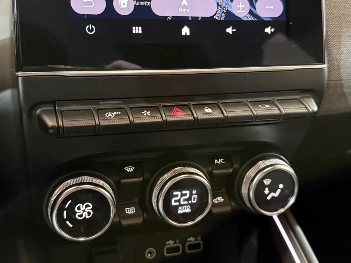 Gros plan sur la console centrale de la Renault Clio Techno TCe 90 2024, montrant les commandes de climatisation et les boutons multifonctions.