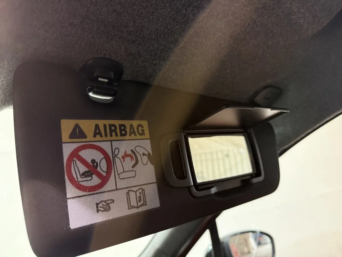 Détail du pare-soleil côté conducteur avec miroir ouvert et avertissement airbag dans une Renault Clio rouge.