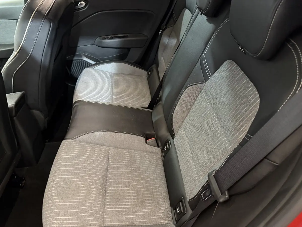 Vue intérieure côté arrière droit montrant la banquette bicolore gris clair et noir de la Renault Clio Techno TCe 90 rouge 2024.