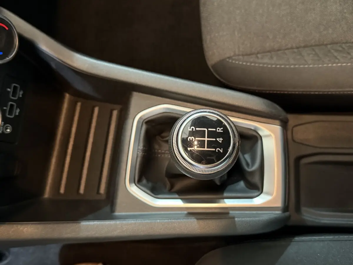 Vue rapprochée de la boîte manuelle noire et argentée de la Renault Clio Business blanche, avec siège tissu gris visible.