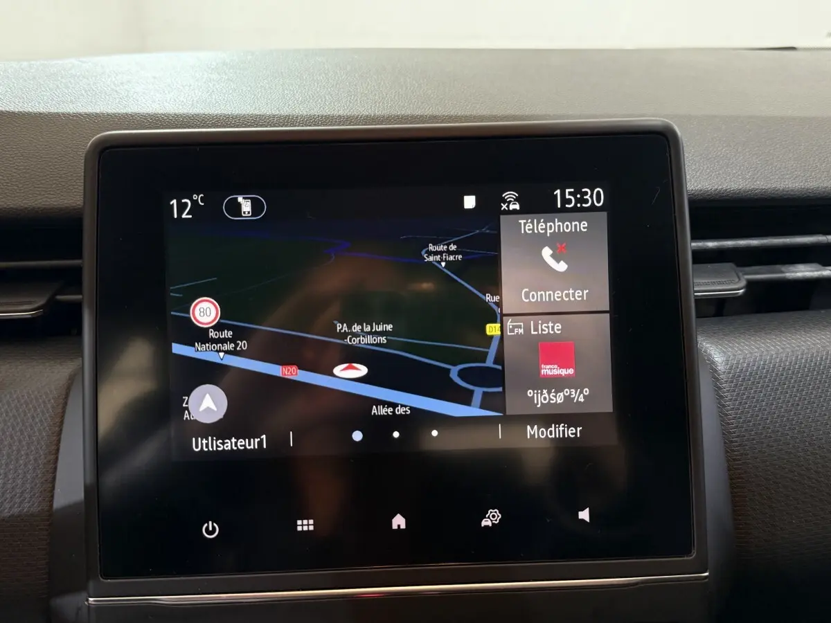 Écran tactile central du tableau de bord de la Renault Clio Business blanc, affichant la navigation et les options multimédia.