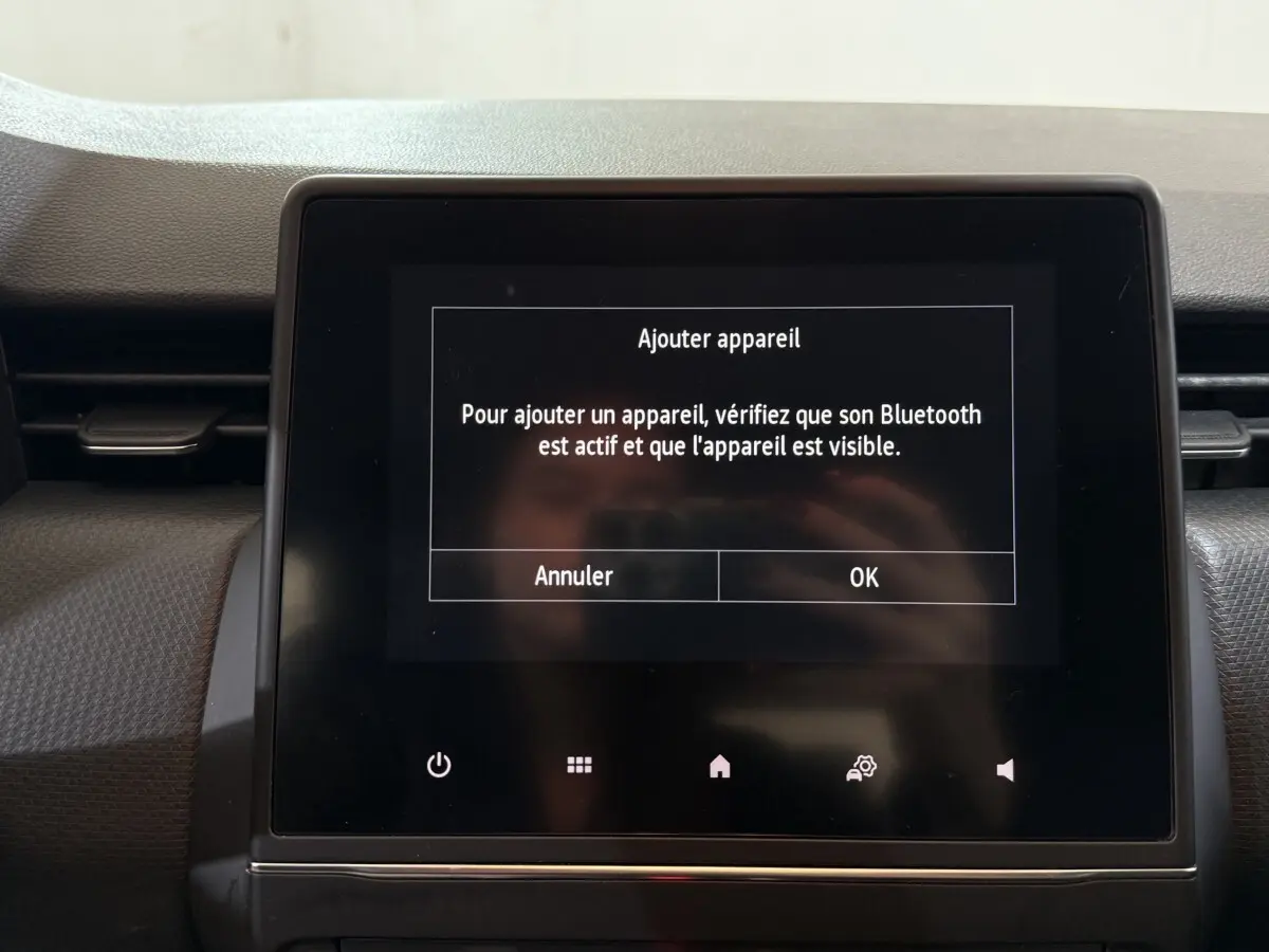Écran tactile central du tableau de bord de la Renault Clio Business blanc, affichant un message Bluetooth.