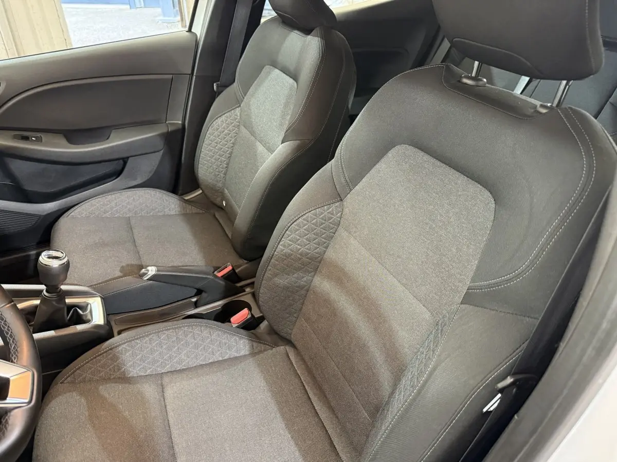 Vue intérieure côté conducteur de la Renault Clio Business 2021, sièges tissu gris avec console centrale et levier de vitesses manuel.