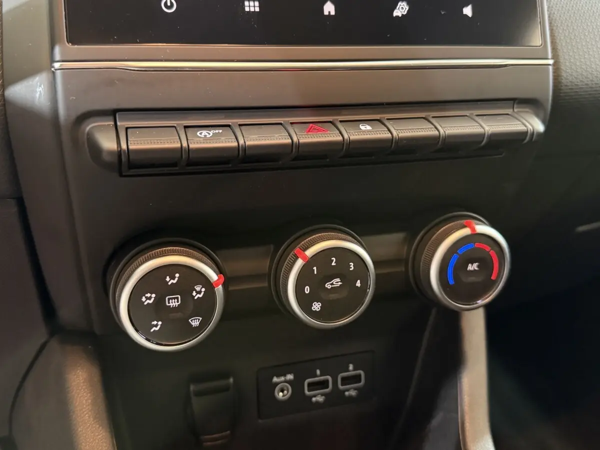 Gros plan sur les commandes de climatisation et ventilation de la Renault Clio Business blanche, tableau de bord noir.