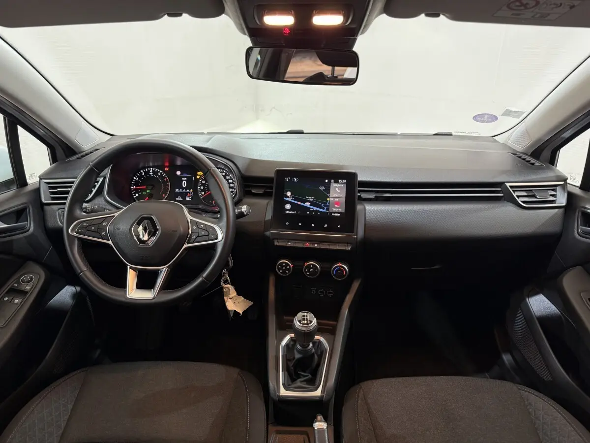 Vue intérieure avant de la Renault Clio Business blanche 2021, tableau de bord avec écran tactile et volant multifonctions cuir synthétique.