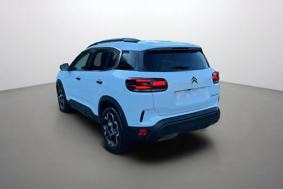 Vue 3/4 arrière gauche d’un Citroën C5 Aircross blanc okénite avec vitres surteintées et jantes alu 18 pouces.
