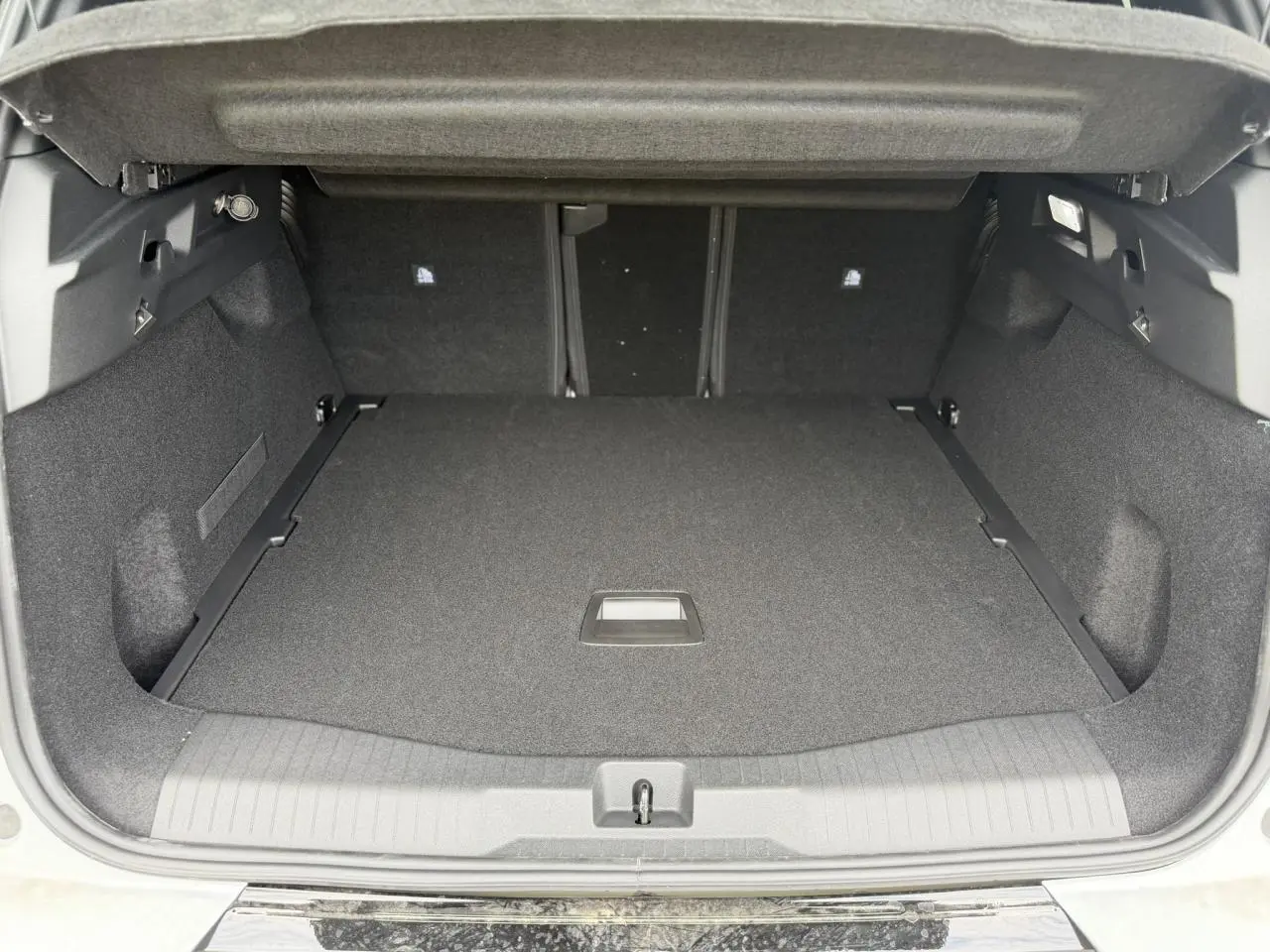 Coffre ouvert vu de l'arrière d'un Citroën C5 Aircross blanc, espace de chargement spacieux et tapis noir.