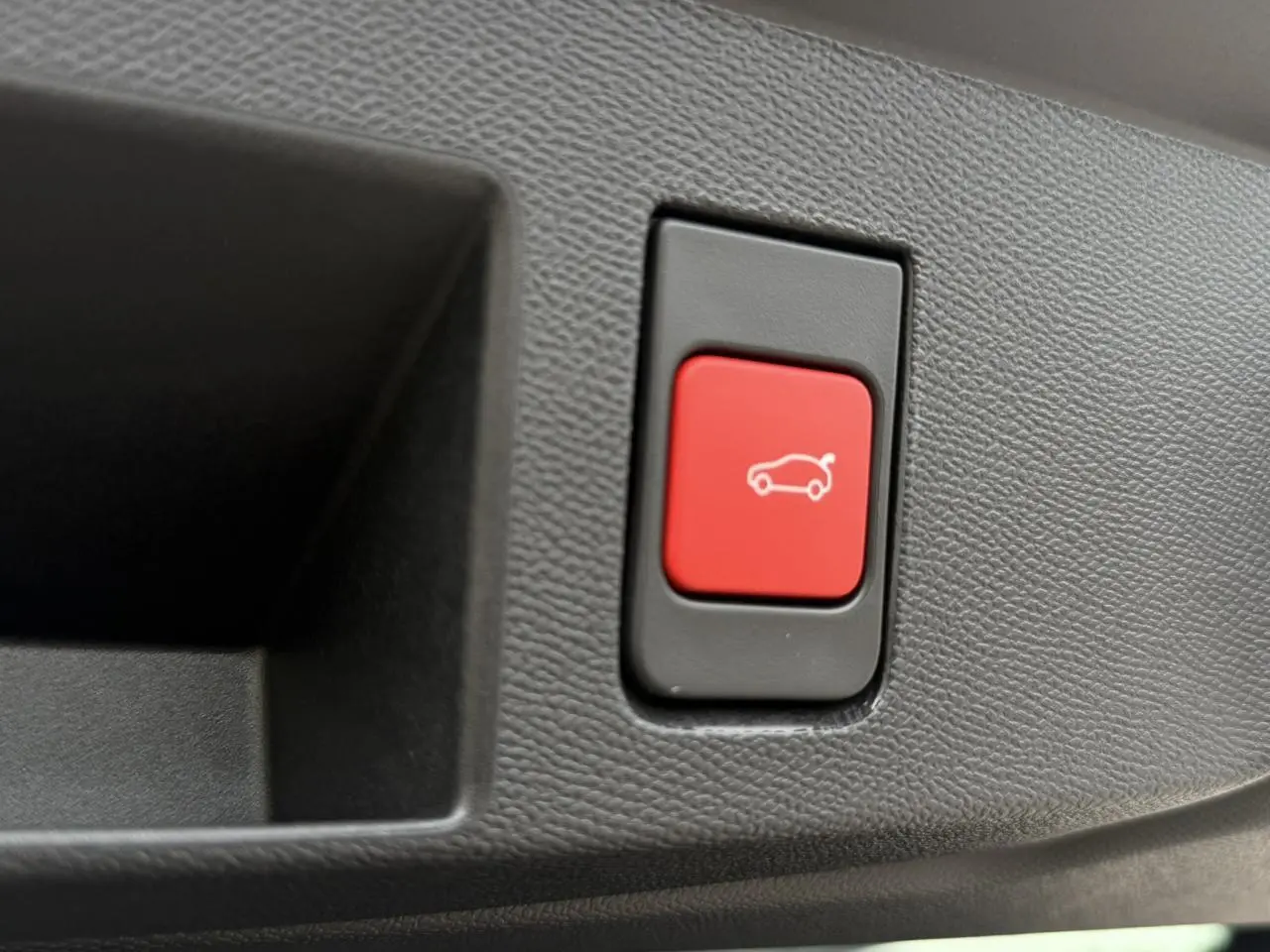 Gros plan sur le bouton rouge d'ouverture électrique du hayon intérieur du Citroën C5 Aircross blanc et noir.