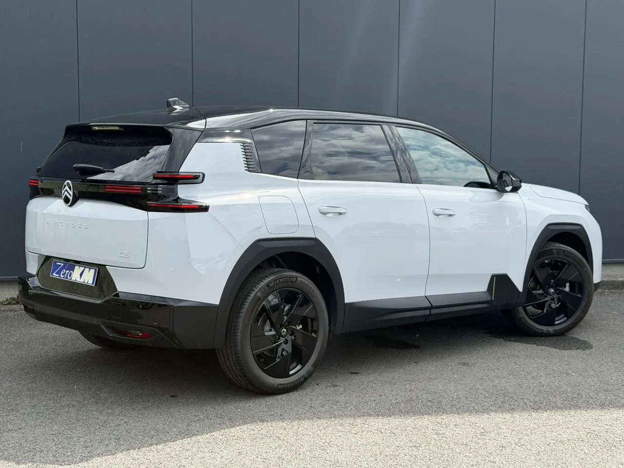 Vue 3/4 arrière droite du Citroën C5 Aircross blanc Okenite avec toit noir et jantes alliage noires.
