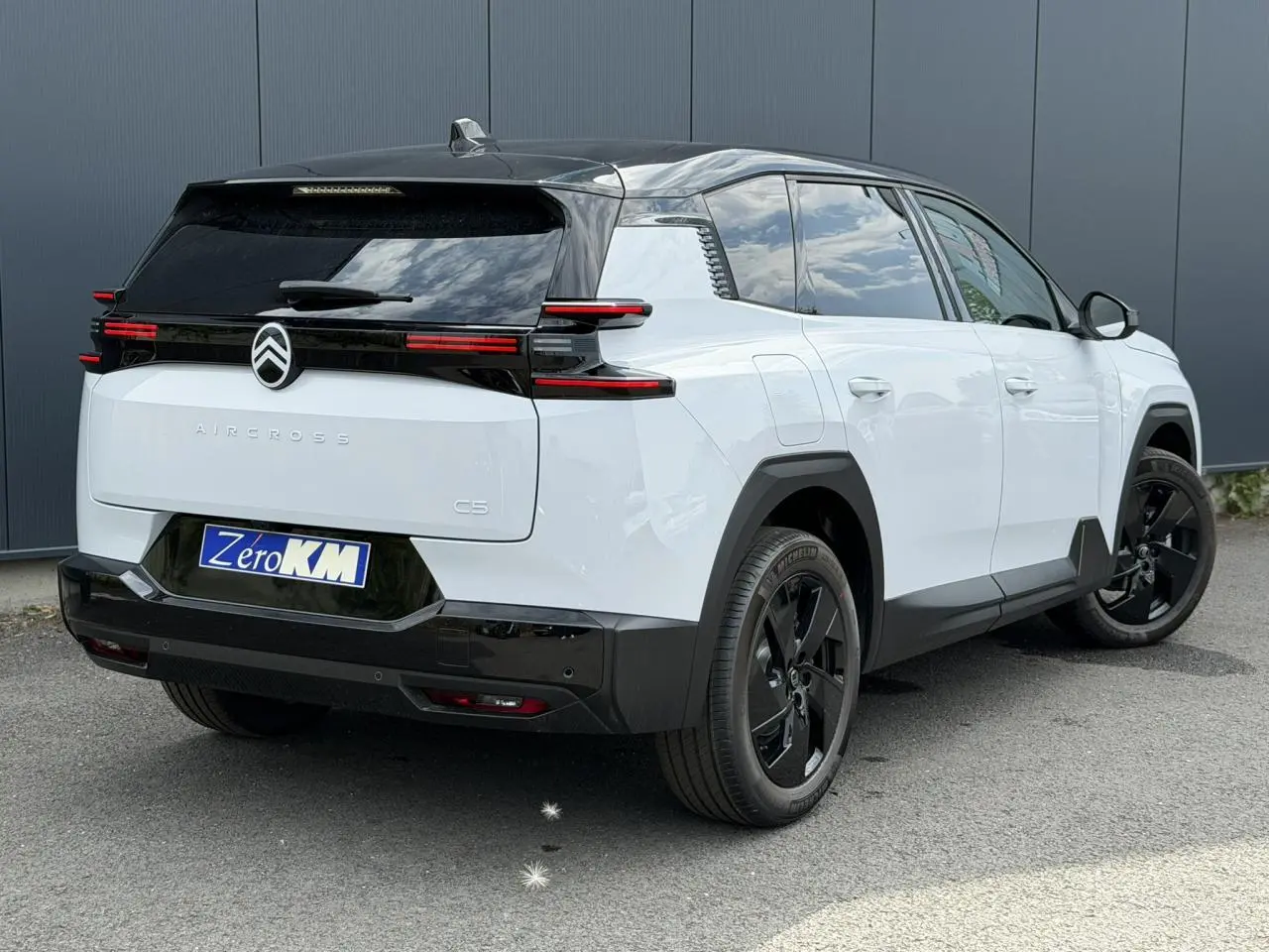 Vue 3/4 arrière droite du Citroën C5 Aircross blanc Okenite avec toit noir et jantes alliage noires.