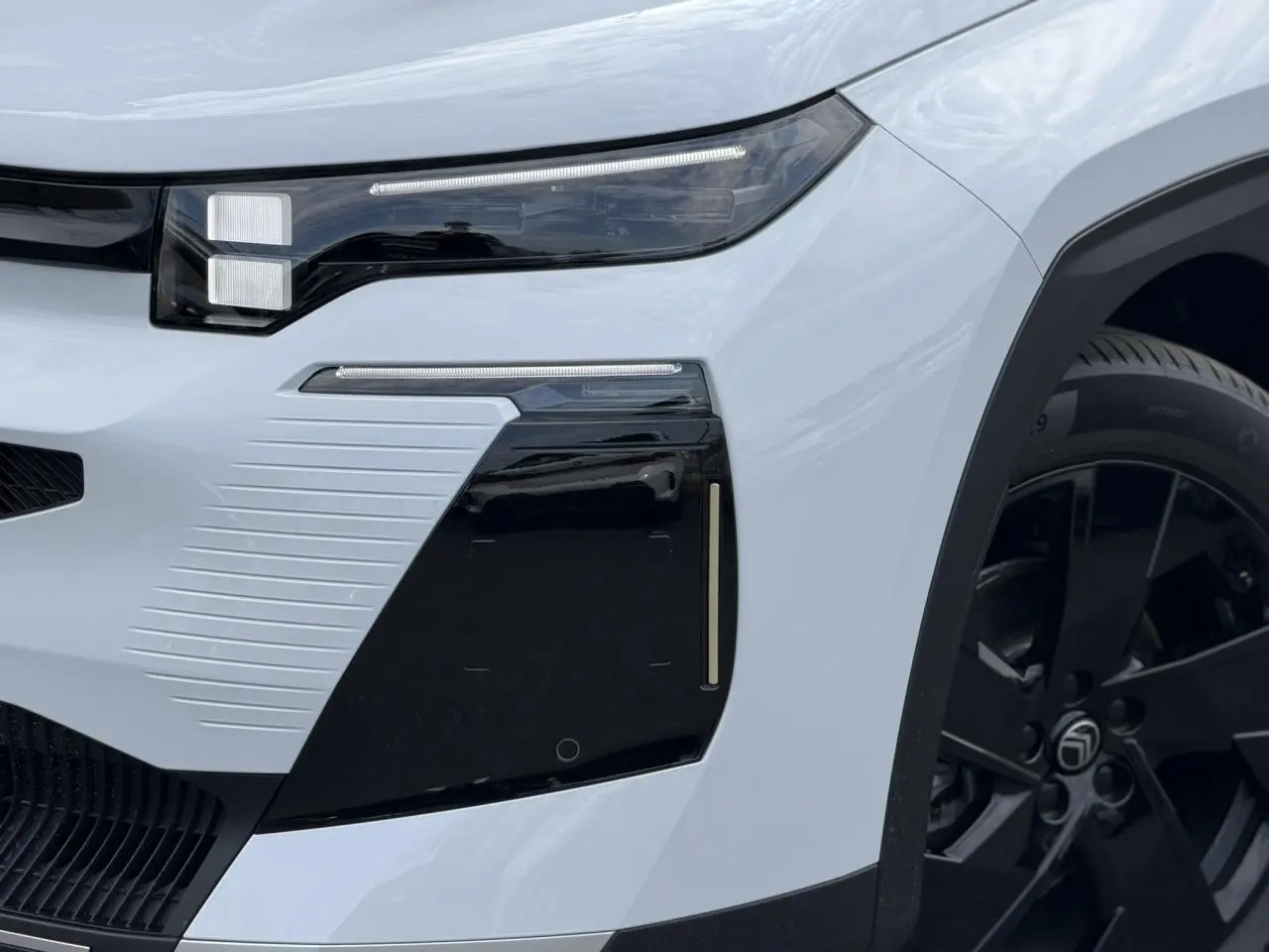 Gros plan sur l'avant droit blanc Okenite du Citroën C5 Aircross 2026 avec optique LED et jante noire.