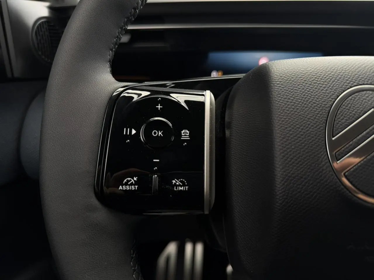 Gros plan sur les commandes noires brillantes au volant cuir du Citroën C5 Aircross hybride 2026.