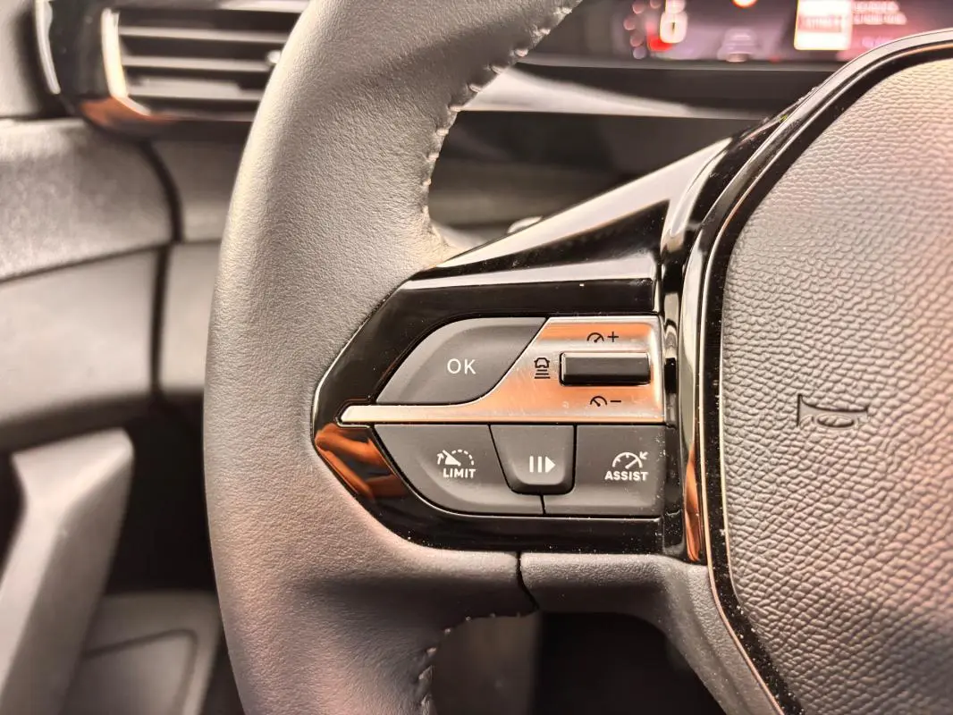 Gros plan sur les commandes à gauche du volant cuir noir du Peugeot 308 Hybrid 145 e-DCS6 Allure 2025.