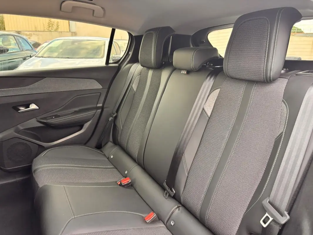 Vue latérale intérieure des sièges arrière gris du Peugeot 308 Hybrid 145 e-DCS6 Allure avec ceintures et appuie-têtes visibles.