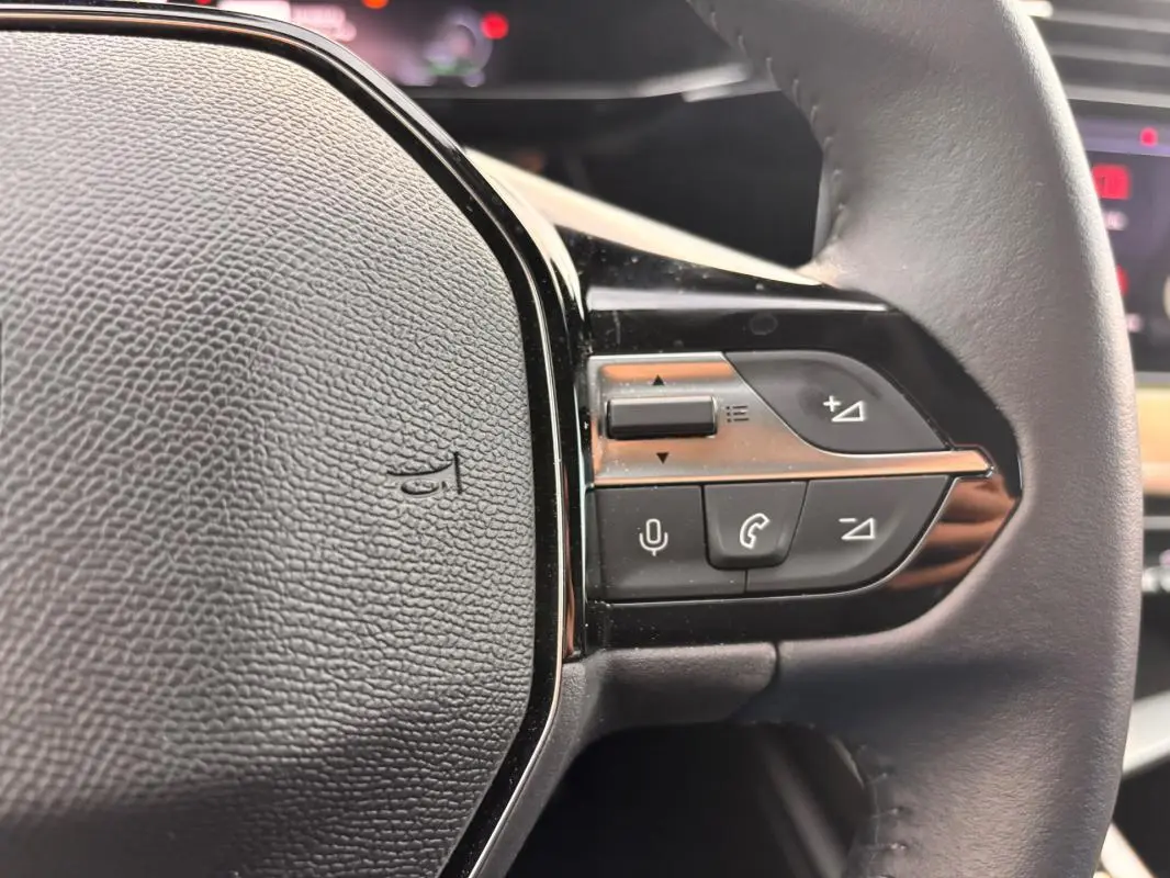 Gros plan sur le volant noir du Peugeot 308 Hybrid 145 e-DCS6 Allure avec commandes audio et téléphone intégrées.
