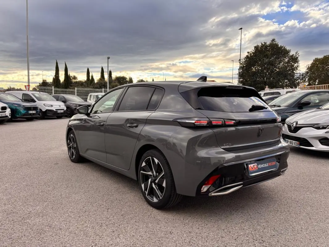 PEUGEOT 308 Hybrid gris vue 3/4 arrière droit, jantes alliage 17 pouces et feux arrière LED allumés.