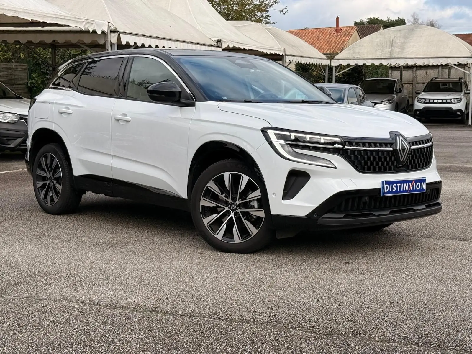 Renault Austral E-Tech 200 blanc nacré avec toit noir, vue 3/4 avant mettant en valeur ses jantes et calandre moderne.