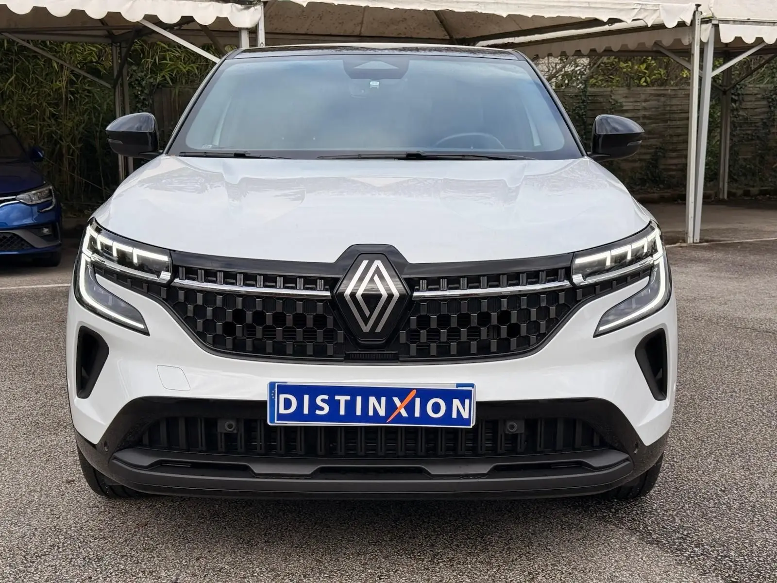 Vue frontale d'un Renault Austral 2023 blanc nacré avec toit noir, calandre noire à motif hexagonal et phares LED distinctifs.