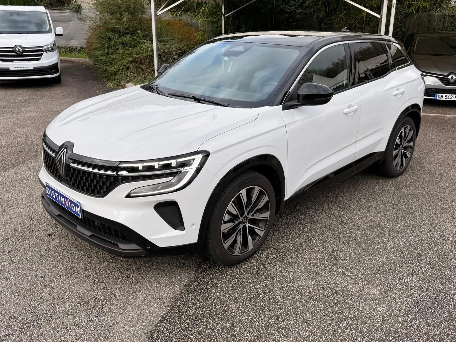 Renault Austral E-Tech 200 hybride blanc nacré avec toit noir, vue 3/4 avant droit, jantes alliage et calandre noire.